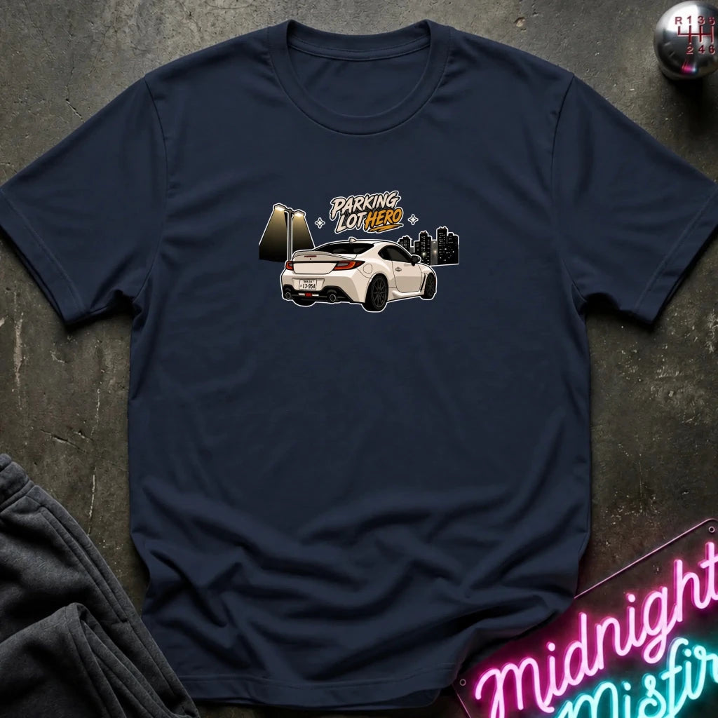 A navy blue crewneck t-shirt laid flat on a dark textured surface, featuring a graphic of a white sports car with the text 'PARKING LOT HERO'