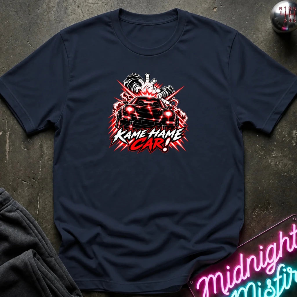 A navy blue short-sleeve t-shirt laid flat on a dark textured surface, featuring a red, white, and black graphic of a car with the text 'Kame Hame Car!' and a neon sign in the corner.