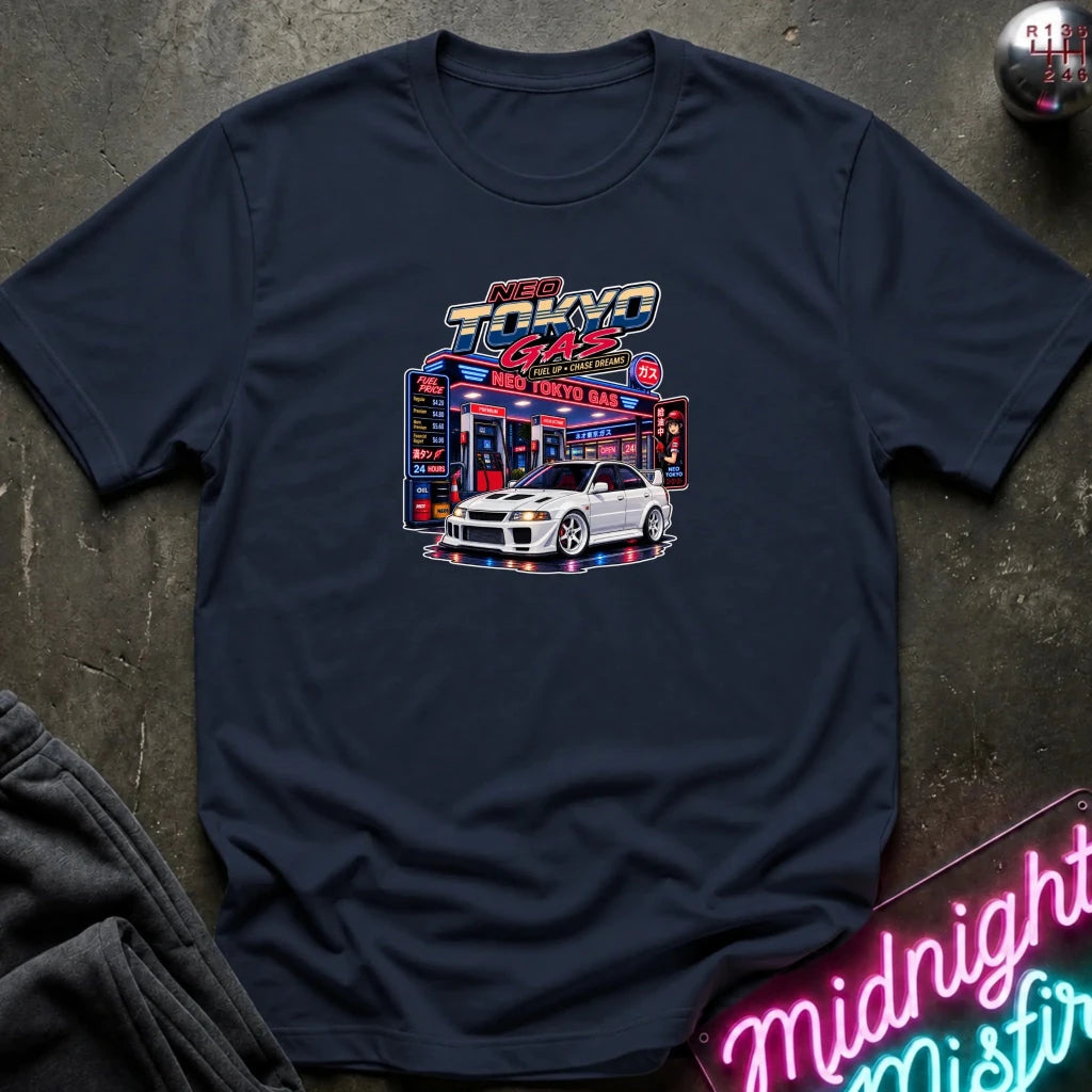  navy short-sleeve crewneck t-shirt featuring a 'Neo Tokyo Gas' graphic with a white sports car, laid flat on a dark textured surface with a neon sign and sweatpants as props.