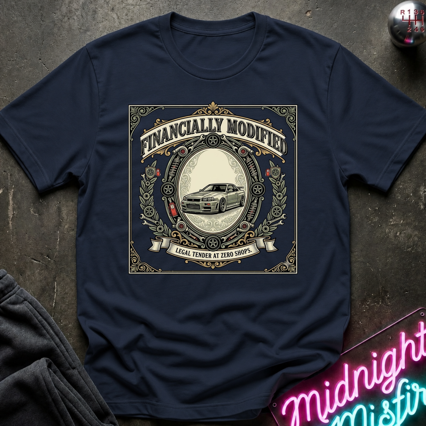 A navy blue short-sleeve t-shirt with a vintage-style graphic print on the front. The graphic features an ornate gold and beige border with the text 'FINANCALLY MODIFIED!' and 'LOCAL TENDER AT ZERO INTEREST' surrounding an illustration of a classic car.