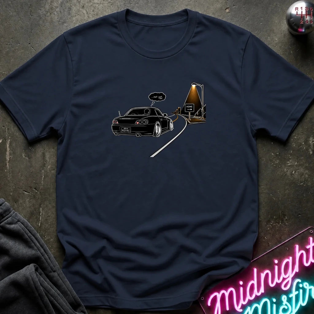 A navy blue short-sleeve t-shirt laid flat on a dark textured surface, featuring a graphic print of a black sports car driving passed sign that says home.