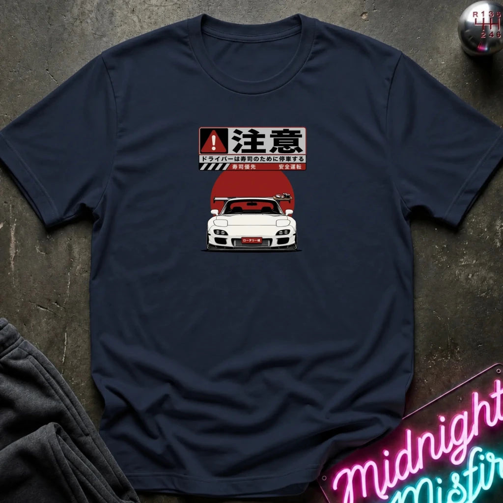 A navy blue crewneck t-shirt laid flat on a dark textured surface. The shirt features a graphic print of a white sports car with a red hood and Japanese text above it.