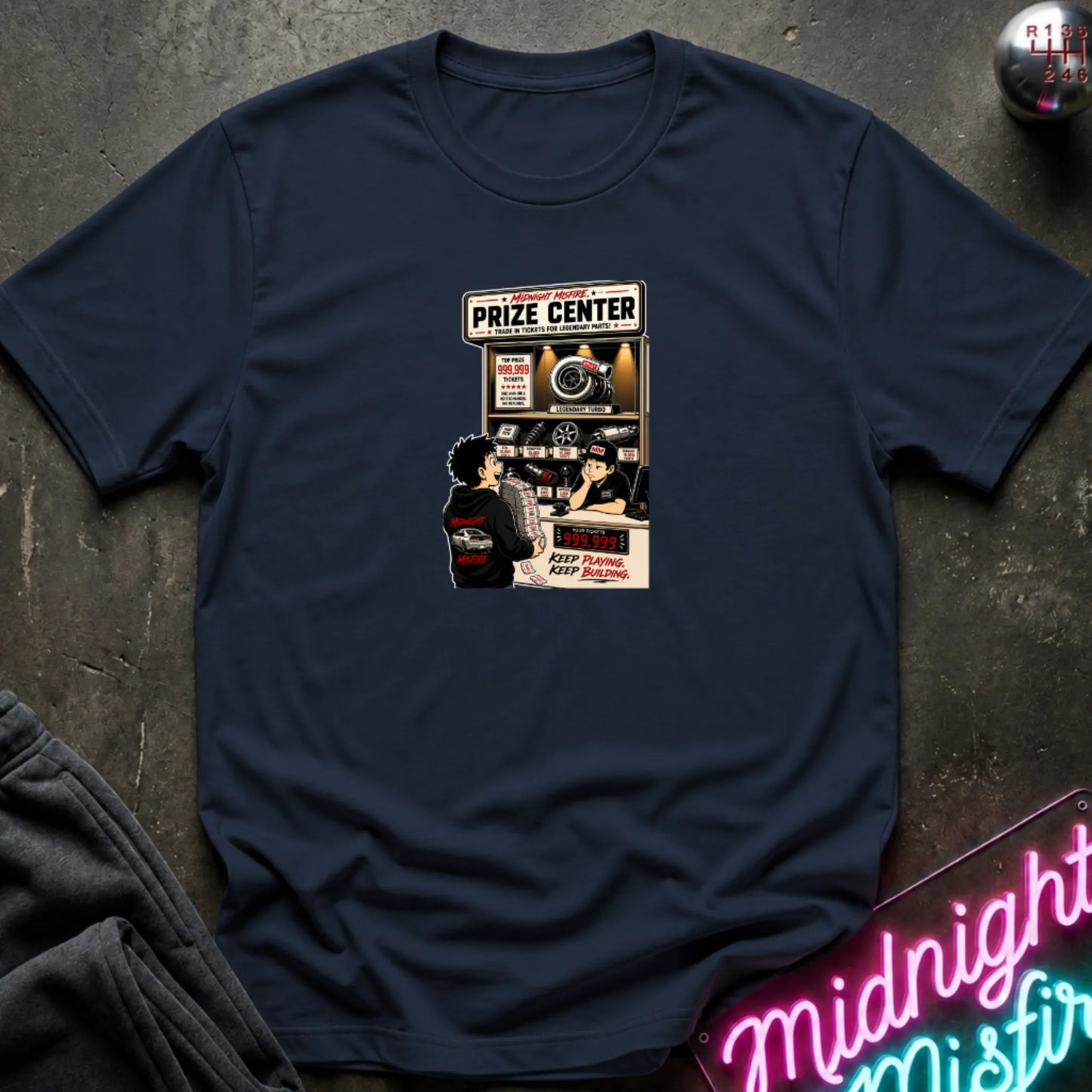 A navy short-sleeve crewneck t-shirt laid flat on a dark textured surface, featuring a central graphic print of a prize center for car parts. 