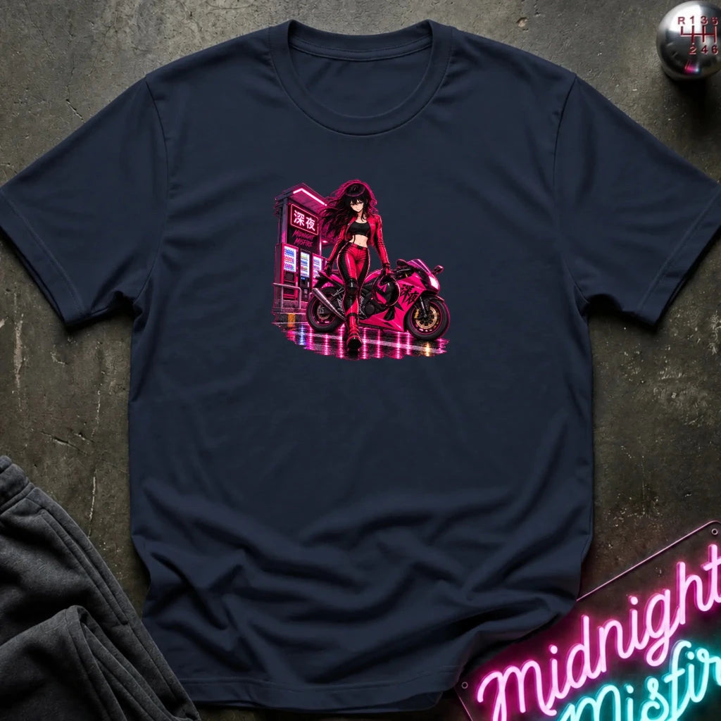A navy blue short-sleeve t-shirt laid flat on a dark textured surface, featuring a colorful graphic print of an anime-style woman in a red outfit standing next to a pink motorcycle in front of a neon-lit building. 