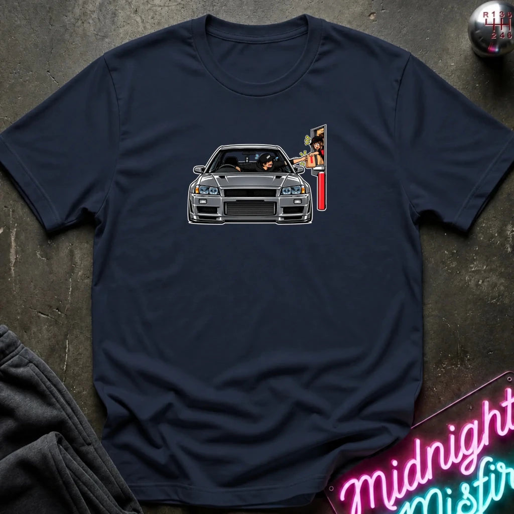 A navy blue crewneck t-shirt featuring a graphic print of a gray sports car with a vertical neon sign on the side, laid flat on a dark textured surface.