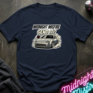A navy blue graphic t-shirt laid flat on a dark textured surface. The shirt features a graphic of a silver sports car with smoke and the text 'MIDNIGHT MISFIRE SEND IT?' in white and black.