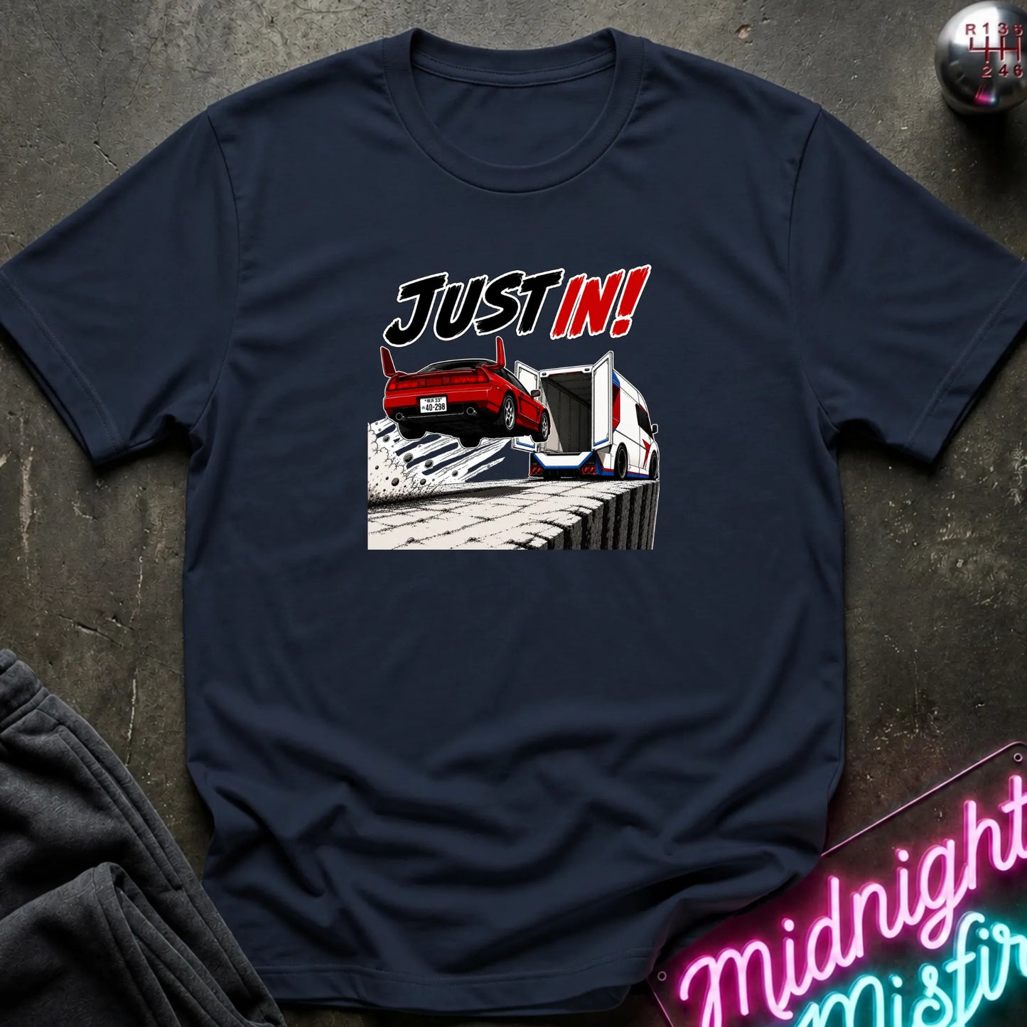 A navy short-sleeved t-shirt  that has a red car jumping into back of another machine.