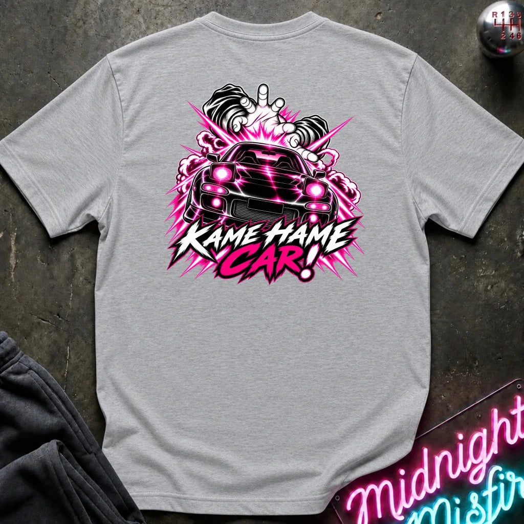 A light gray heather crewneck t-shirt laid flat on a dark textured surface, featuring a vibrant graphic on the back with a black car, pink and white energy effects, and the text 'KAME HAME CAR!'.