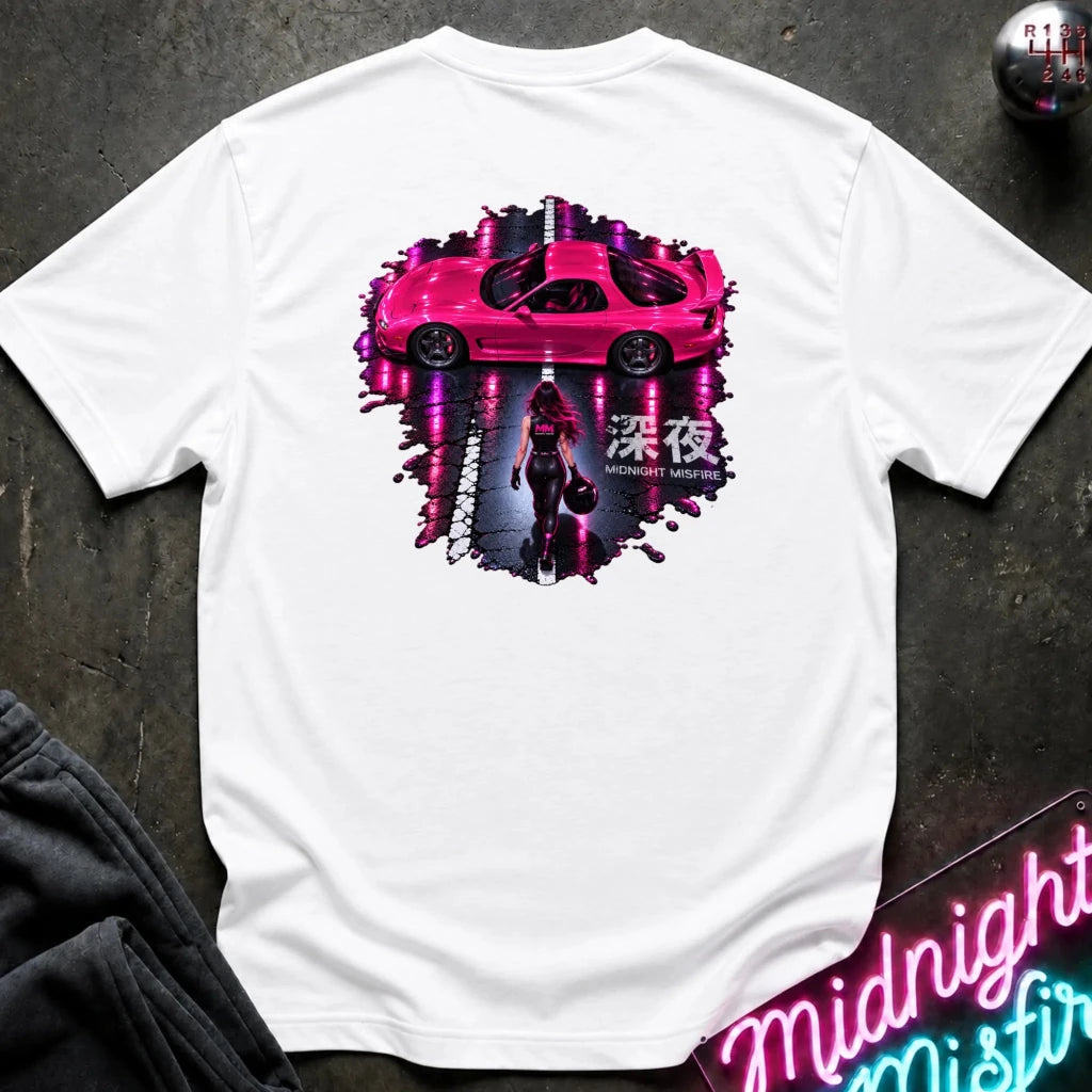 A white short-sleeve t-shirt laid flat on a dark textured surface, featuring a large graphic print on the back with a pink sports car, a dark figure, neon-style vertical light streaks, and Japanese characters. 