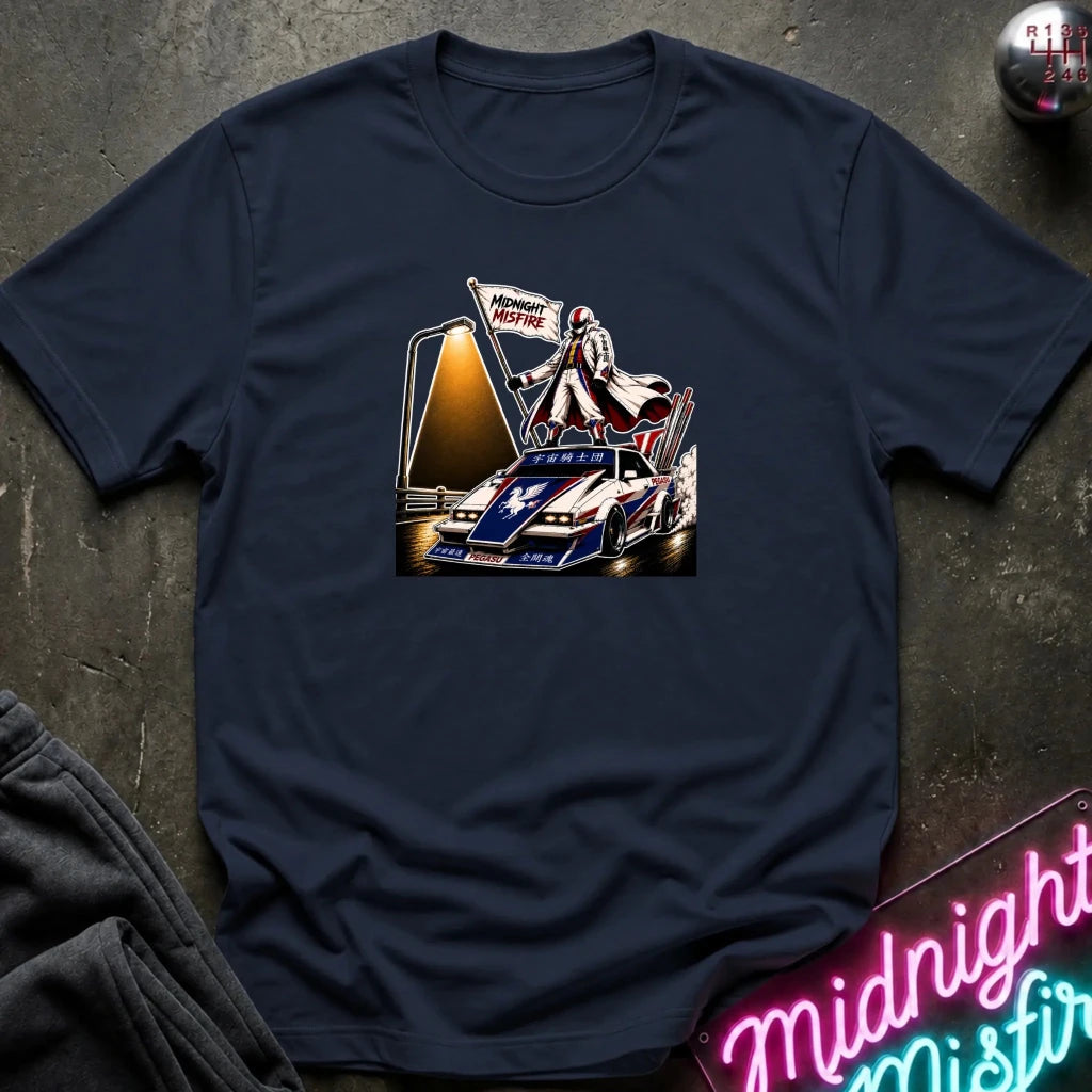 A navy blue short-sleeve t-shirt laid flat on a dark textured surface, featuring a detailed graphic print of a vintage race car with a driver and a 'Midnite Misfire' flag. 