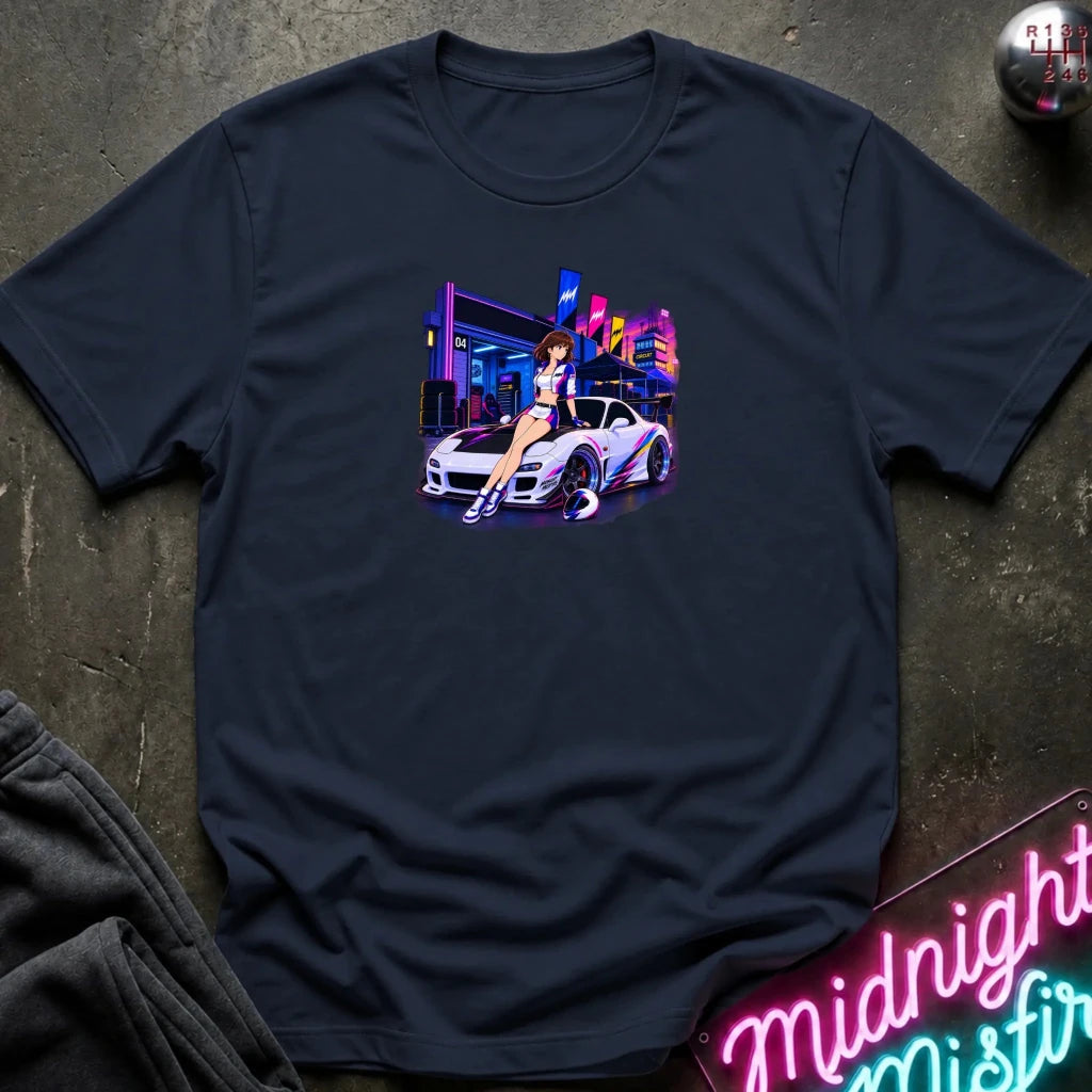 A navy blue  short-sleeve t-shirt laid flat on a dark textured surface, featuring a colorful graphic print of a white sports car and a woman in a neon-lit scene. 