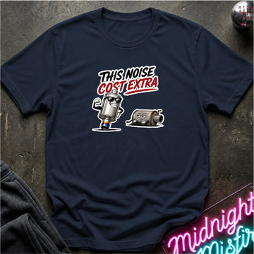 A navy blue graphic t-shirt laid flat on a dark textured surface. The shirt features a cartoon graphic with the text 'THIS NOISE COST EXTRA' in white and red.