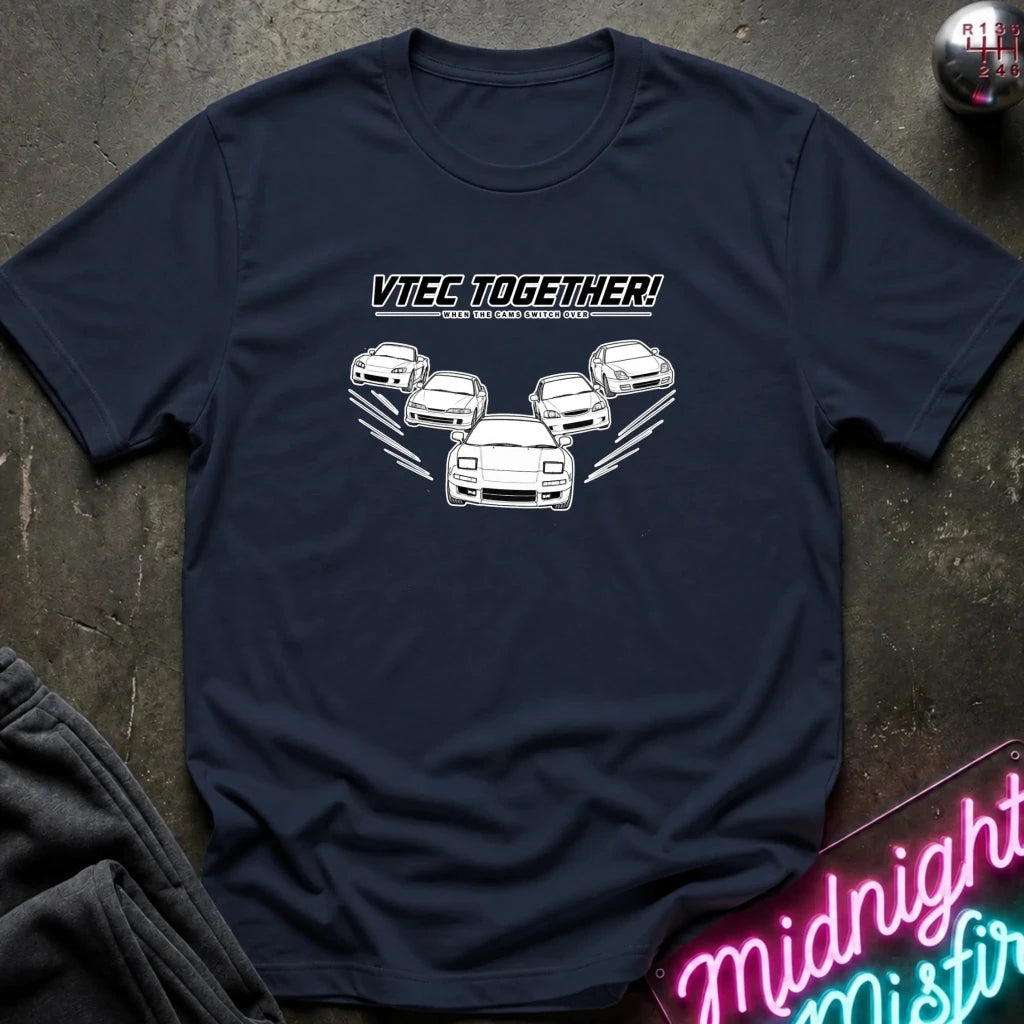 A navy blue graphic t-shirt laid flat on a dark textured surface. The shirt features a white graphic of five cars with the text 'VITEC TOGETHER!' 