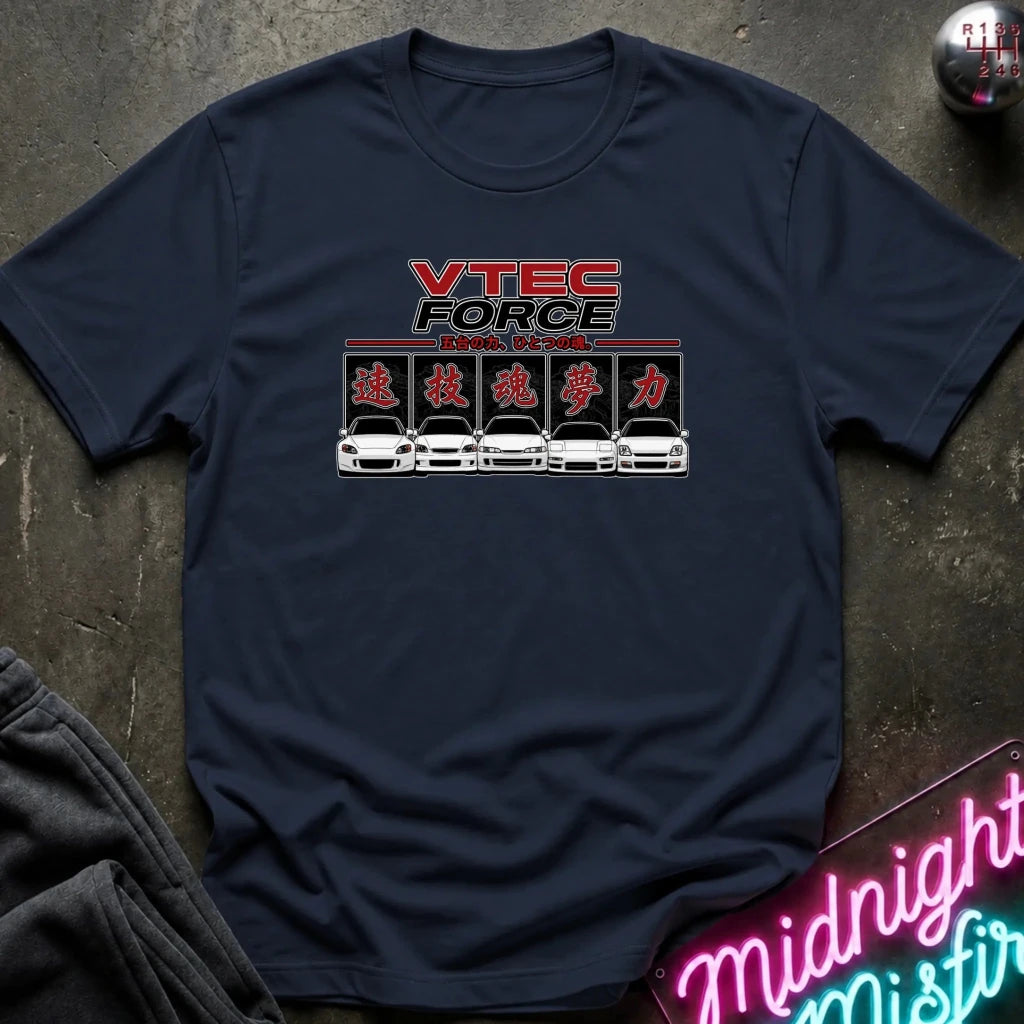 A navy blue short-sleeve t-shirt laid flat on a dark textured surface. The shirt features a graphic print on the chest with the text 'VTEC FORCE' in red and black, Japanese katakana characters, and a row of white sports cars.