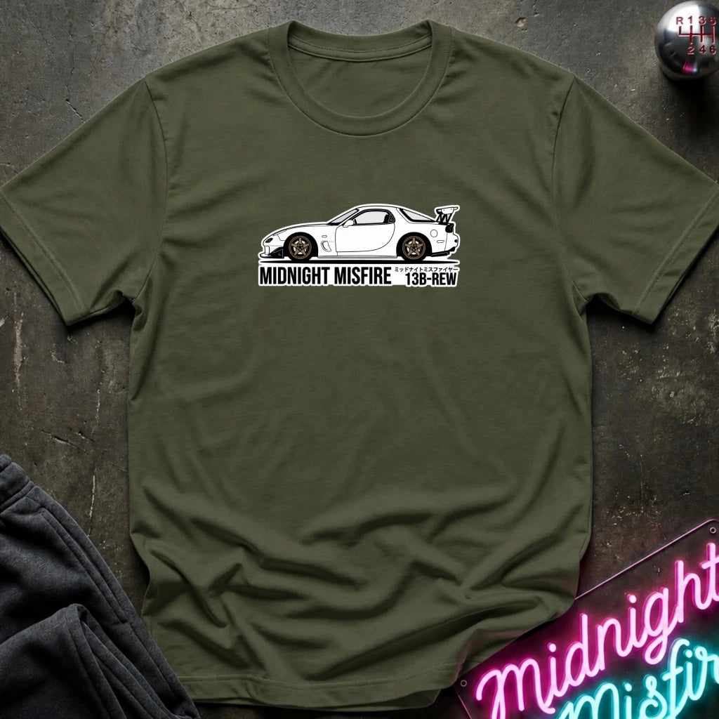 olive green short-sleeve t-shirt laid flat on a dark textured surface, featuring a white sports car graphic and the text 'MIDNIGHT MISFIRE '