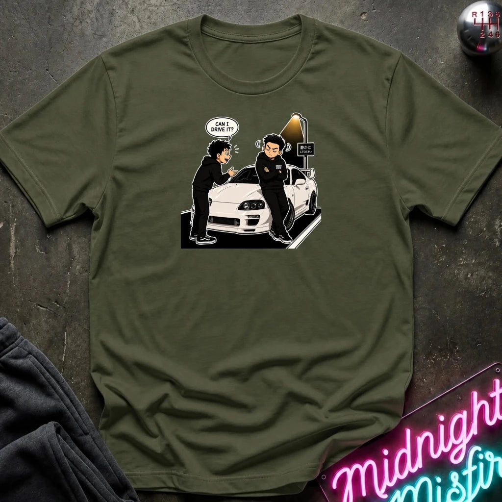 An olive green crewneck t-shirt laid flat on a dark textured surface, featuring a cartoon graphic of two anime characters standing next to a white sports car with a speech bubble