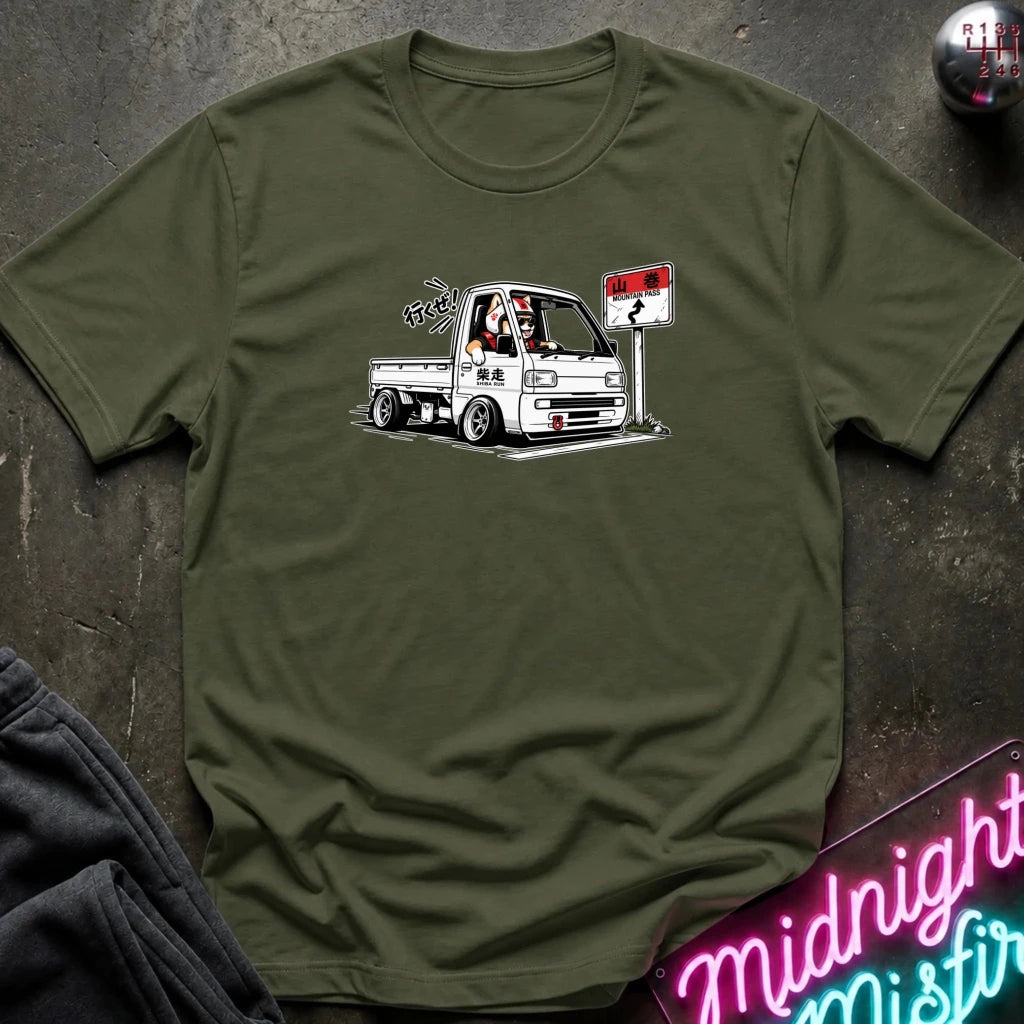 olive green short-sleeve crewneck t-shirt laid flat on a dark textured surface. The shirt features a graphic print of shiba inu dog.
