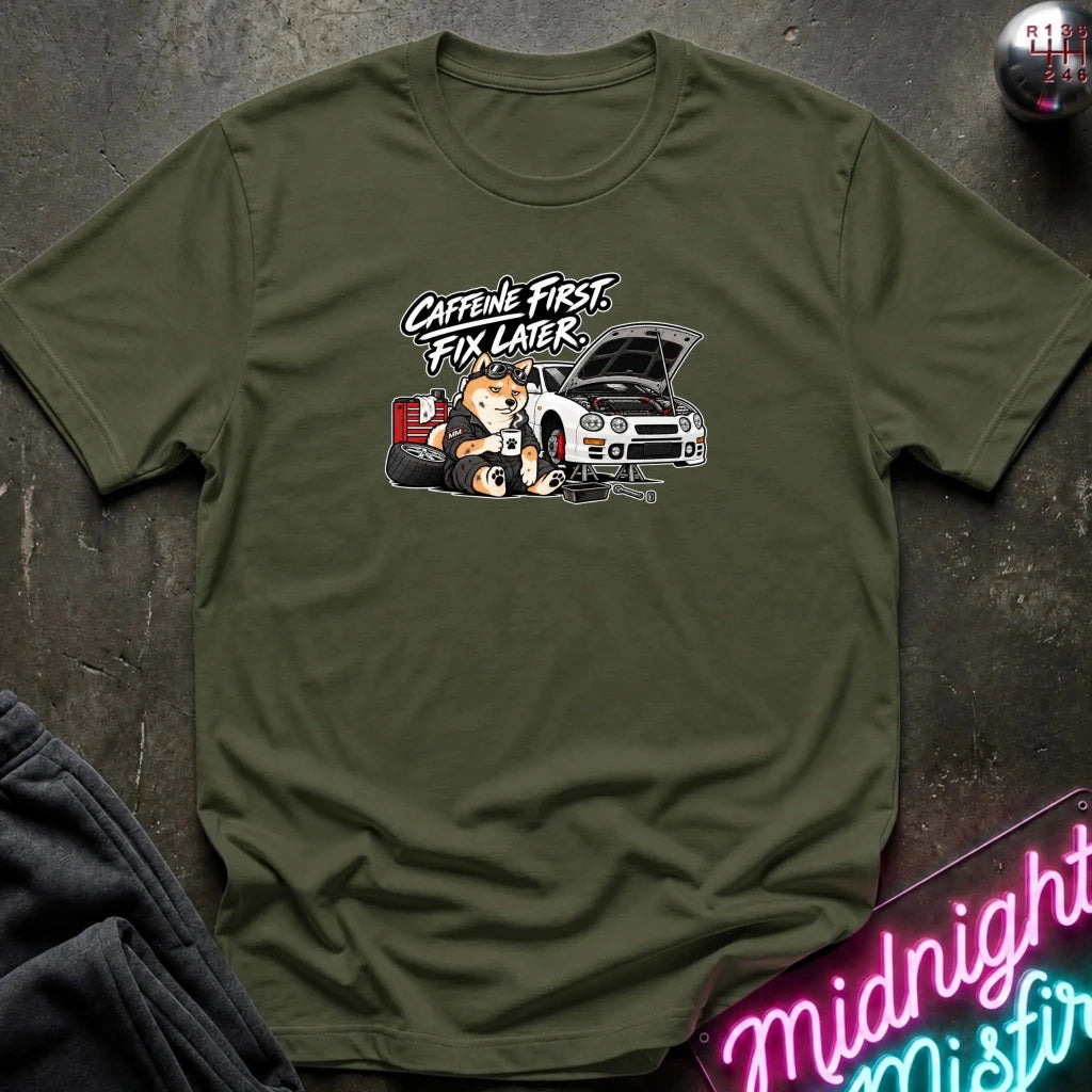 olive short-sleeve crewneck t-shirt laid flat on a dark textured surface. The shirt features a graphic print of shiba inu dog.