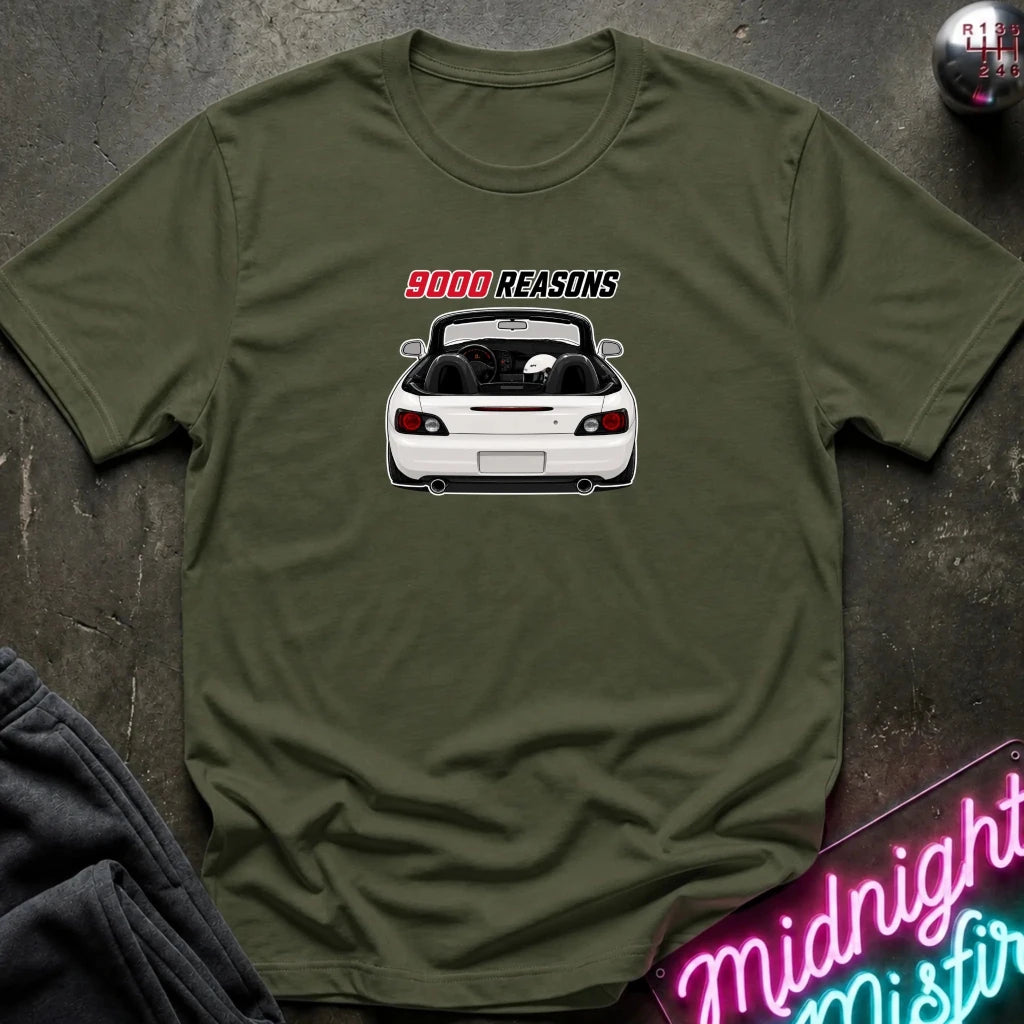 An olive green crewneck t-shirt featuring a graphic of a white convertible sports car with the text '9000 REASONS' above it, laid flat on a dark textured surface.