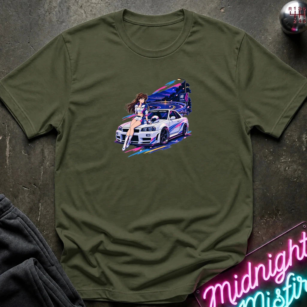 An olive green  short-sleeve t-shirt laid flat on a dark textured surface, featuring a colorful graphic print of a white sports car and a woman in a neon-lit scene. 