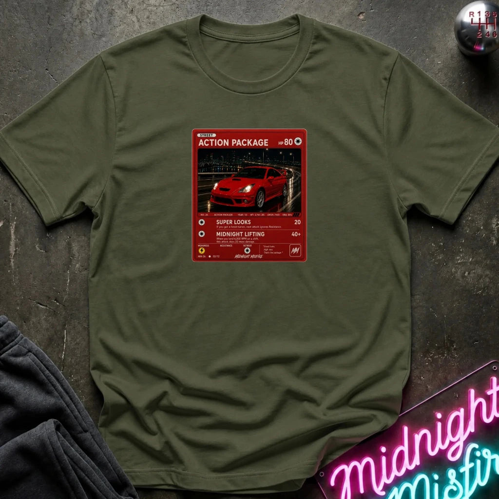 An olive green crewneck t-shirt laid flat on a dark textured surface, featuring a red graphic print vintage card and a car.
