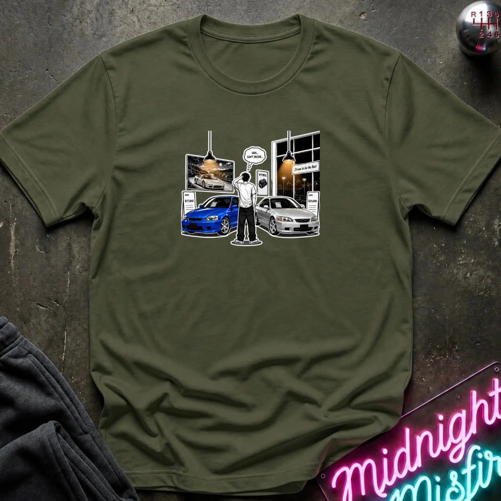 An olive green short-sleeve crewneck t-shirt laid flat on a dark textured surface. The center of the shirt features a graphic print depicting a scene with a blue and silver  sports cars