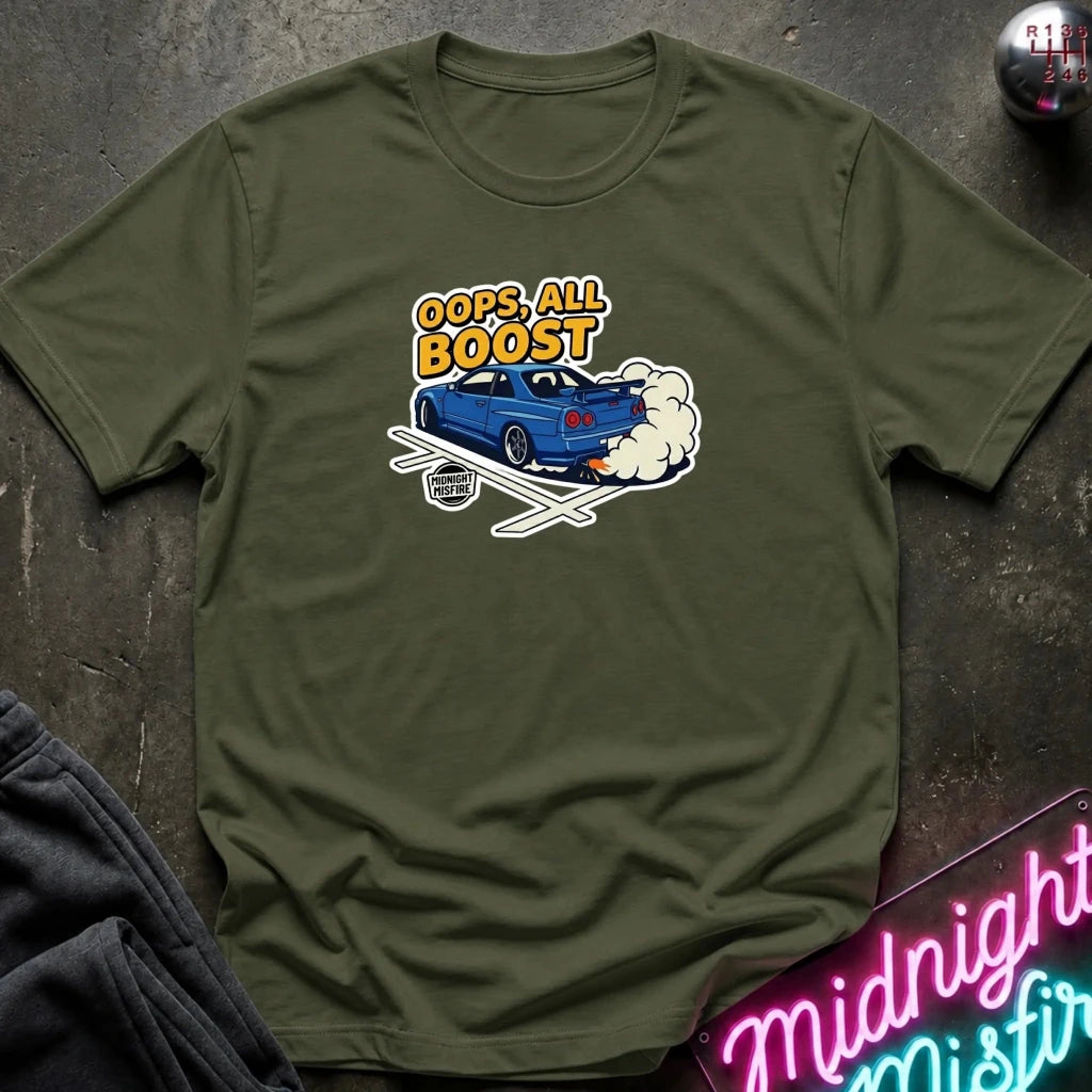 An olive green crewneck t-shirt laid flat on a dark textured surface, featuring a graphic of a blue car with the text 'OOPS. ALL BOOST.
