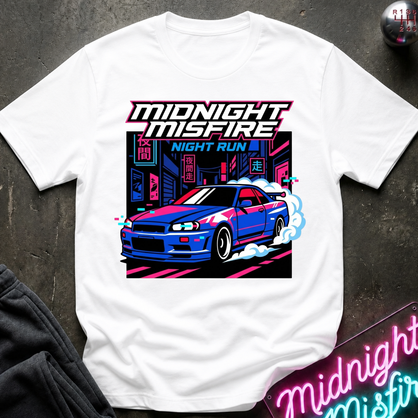 A white short-sleeve graphic t-shirt featuring a vibrant neon-style print of a blue sports car with pink and white accents, set against a dark gray textured background with decorative props.