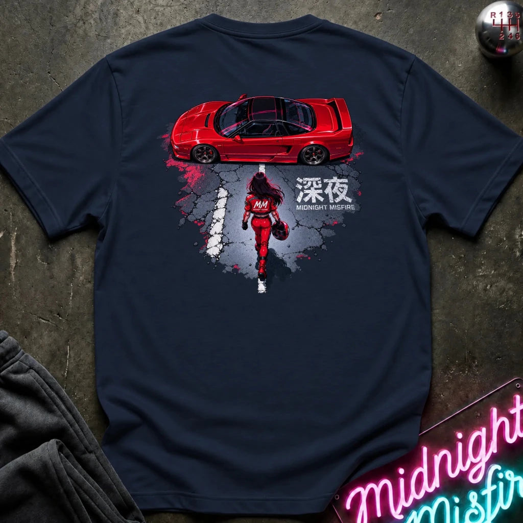 A navy blue short-sleeve graphic T-shirt laid flat on a dark textured surface. The shirt features a large back print showing a red sports car above a red racer in a splattered gray and black design