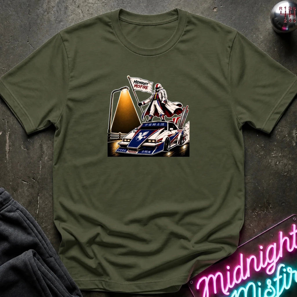 An olive green short-sleeve t-shirt laid flat on a dark textured surface, featuring a detailed graphic print of a vintage race car with a driver and a 'Midnite Misfire' flag. 