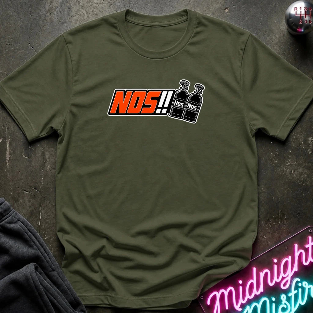 An olive green crewneck t-shirt laid flat on a dark textured surface. The shirt features a graphic print on the chest with the text 'NOS!!' in orange and white, alongside two black spray bottles labeled 'NOS'.