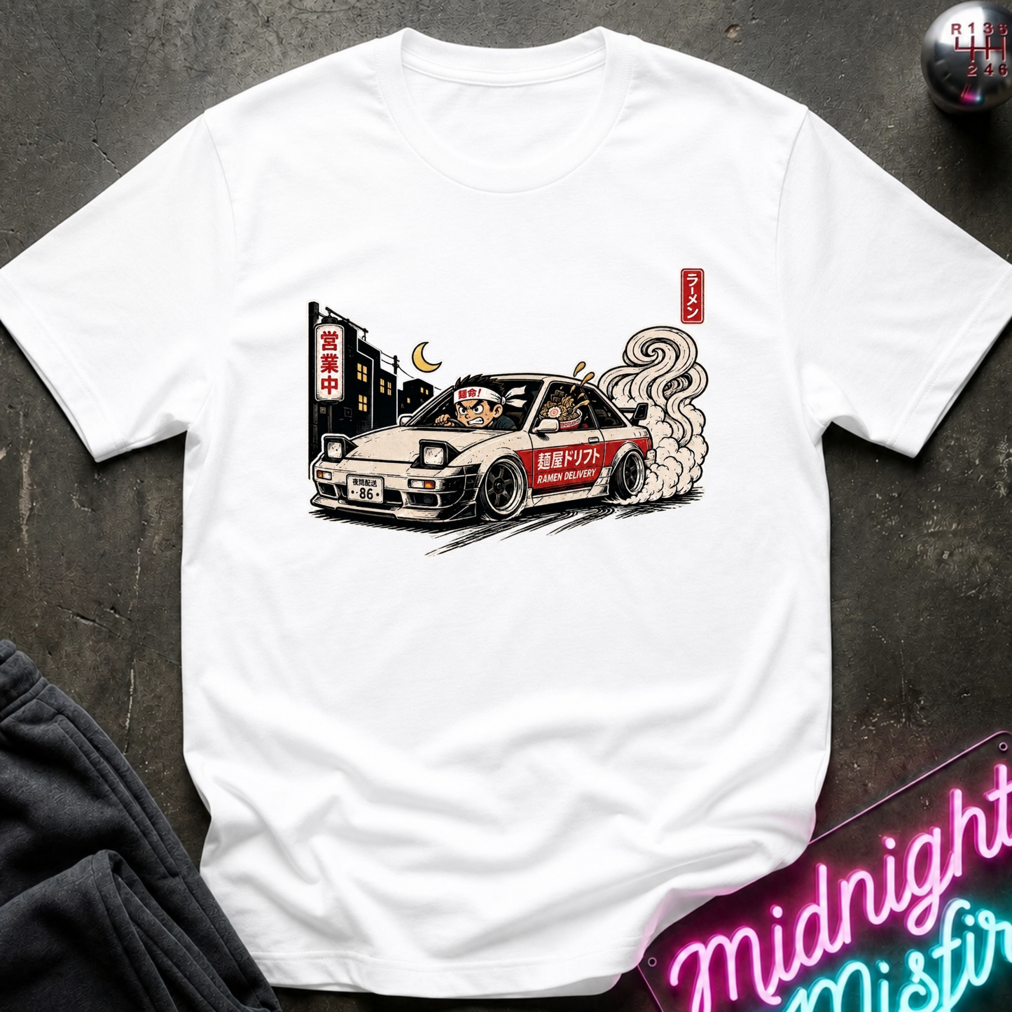 A white short-sleeve crewneck t-shirt featuring a graphic print of a beige and red drift car with smoke, displayed flat on a dark textured surface.