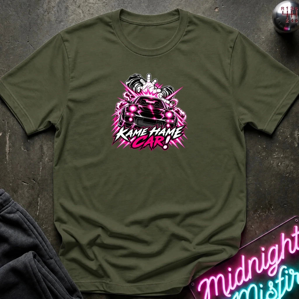 olive short-sleeve graphic t-shirt laid flat on a dark textured surface. The shirt features a red, white, and black graphic of a car with the text 'KAME HAME CAR!' in stylized lettering.