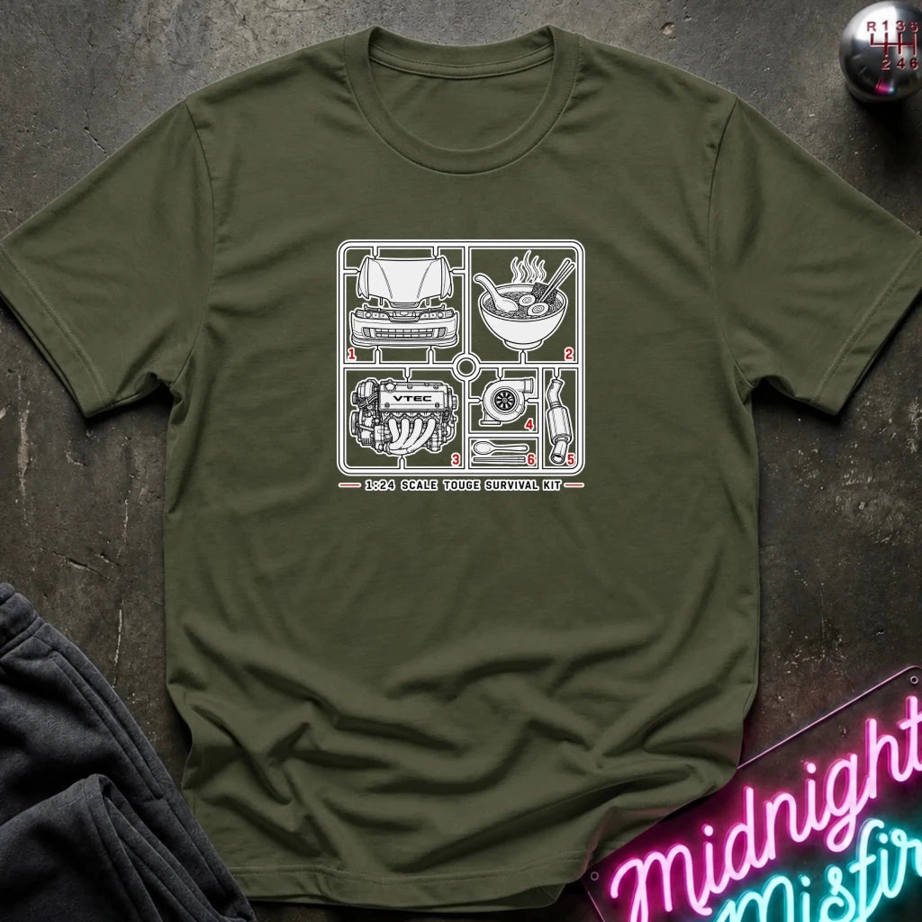 An olive green crewneck t-shirt with a white graphic print of classic car and motorcycle parts, laid flat on a dark textured surface with a neon sign and dark pants in the background.