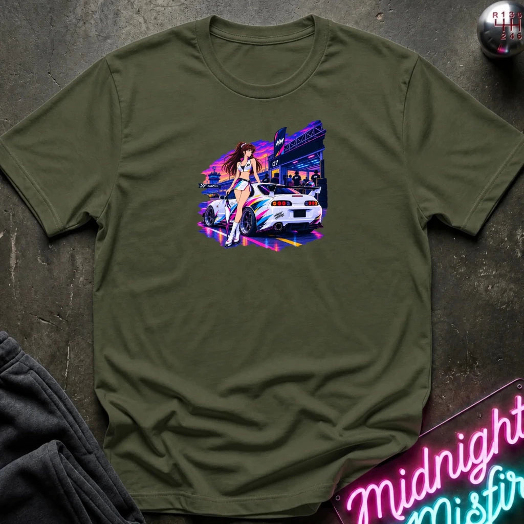 An olive green short-sleeve t-shirt laid flat on a dark textured surface, featuring a colorful graphic print of a white sports car and a woman in a neon-lit scene. 