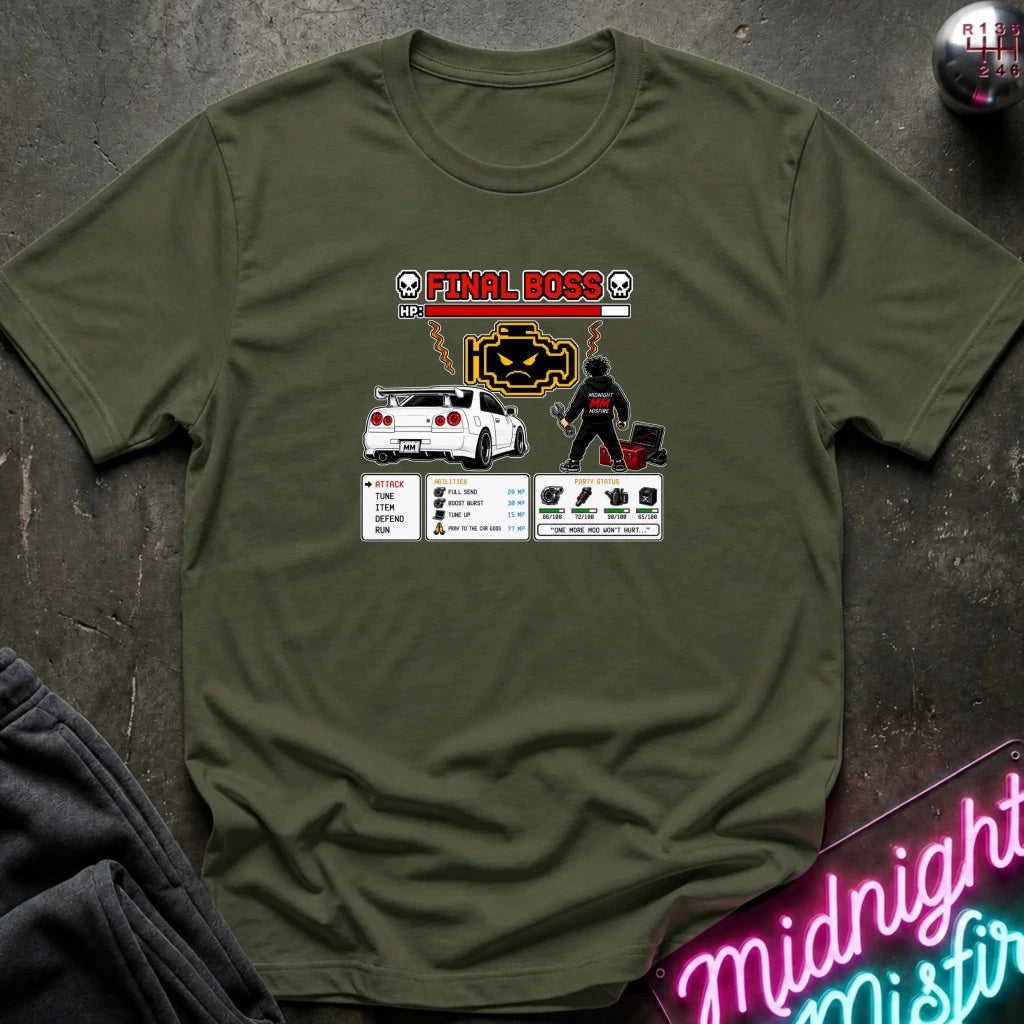 A olive green graphic t-shirt laid flat on a dark textured surface. The shirt features a 'Final Boss' engine design inspired by the rpg game.