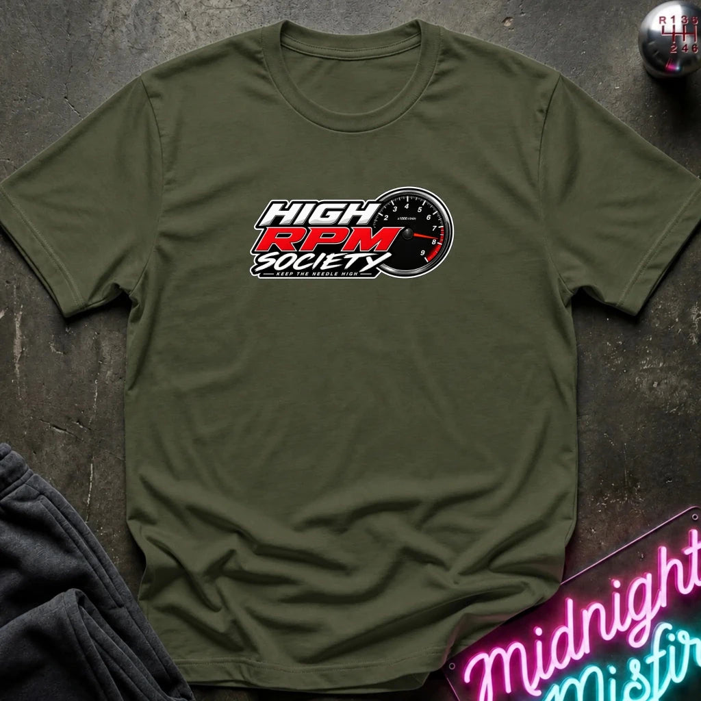 An olive green crewneck t-shirt featuring a 'High RPM Society' graphic on the chest, styled flat on a dark textured surface with a neon sign and clothing prop.