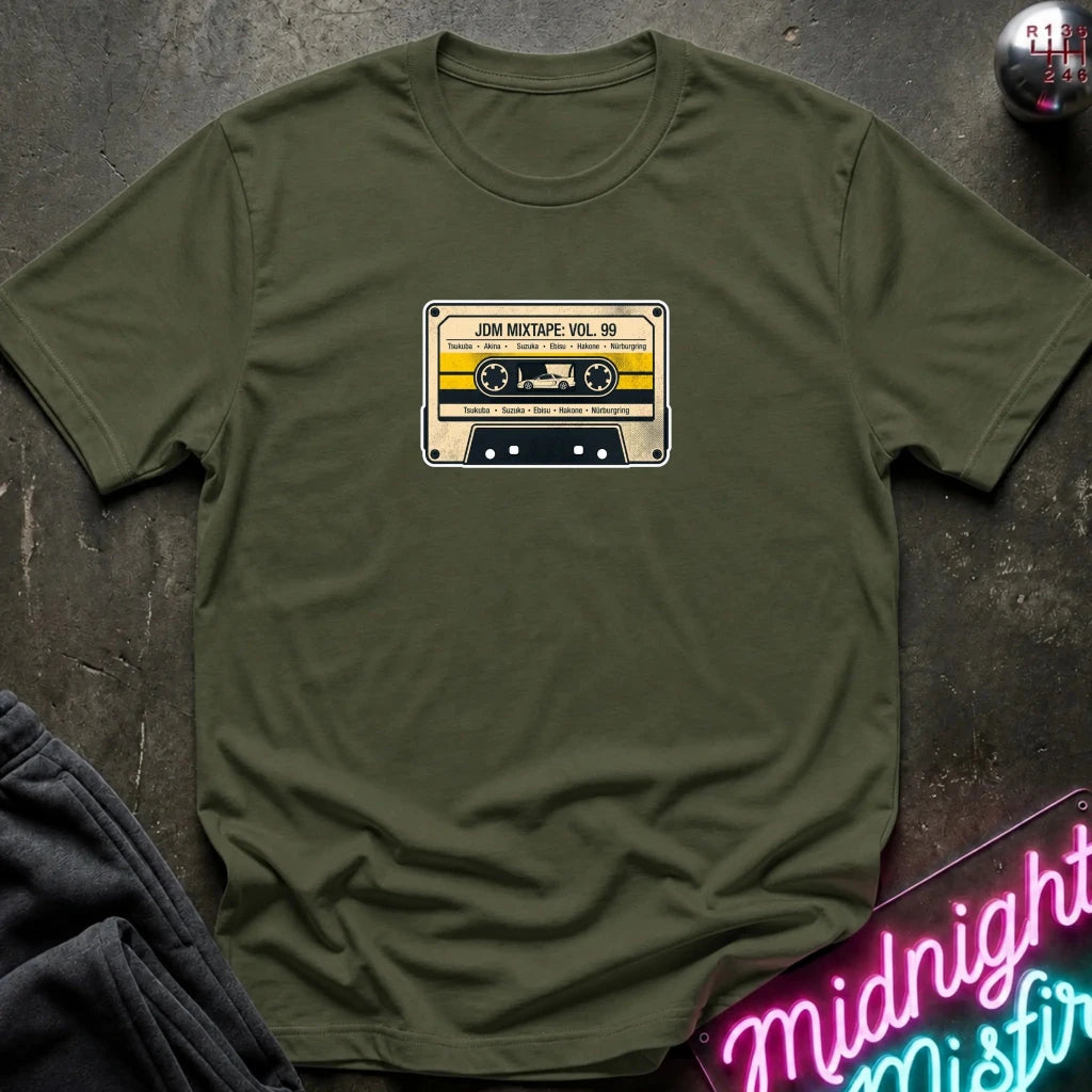 olive green crewneck t-shirt laid flat on a dark textured surface, featuring a retro cassette tape graphic on the chest with the text 'JDM MIXTAPE VOL.