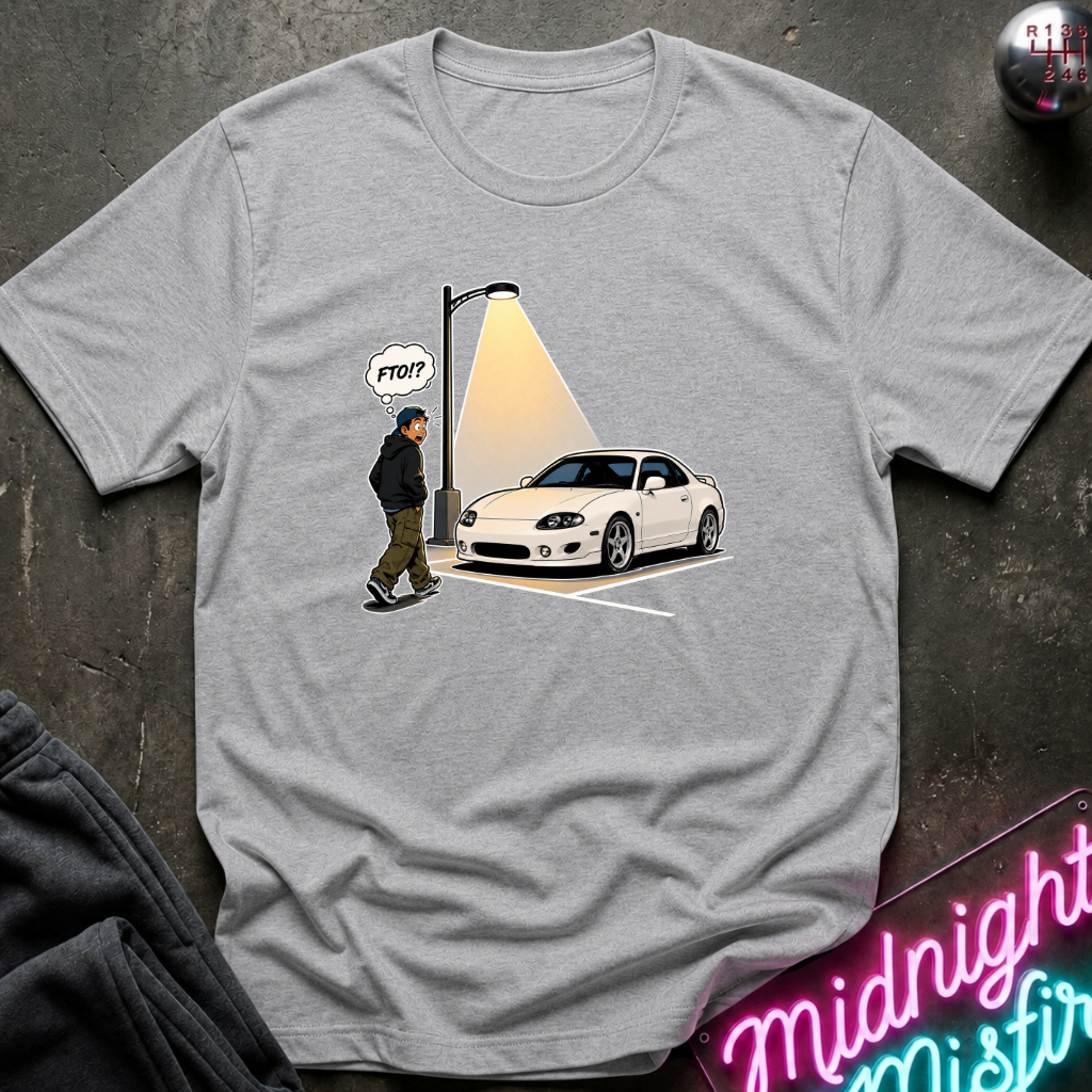 A heather gray short-sleeve t-shirt with a graphic print of a white sports car parked under a streetlamp with a figure walking in the shadow, styled flat-lay on a dark textured surface with a neon sign and sweatpants.