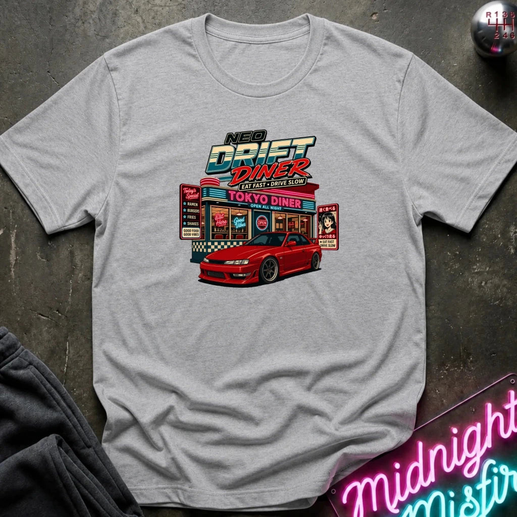 A light gray heather crewneck t-shirt featuring a colorful graphic print of a red sports car parked in front of a retro 'Nex Drift Diner' on a dark textured concrete floor, styled with a neon sign and dark sweatpants.
