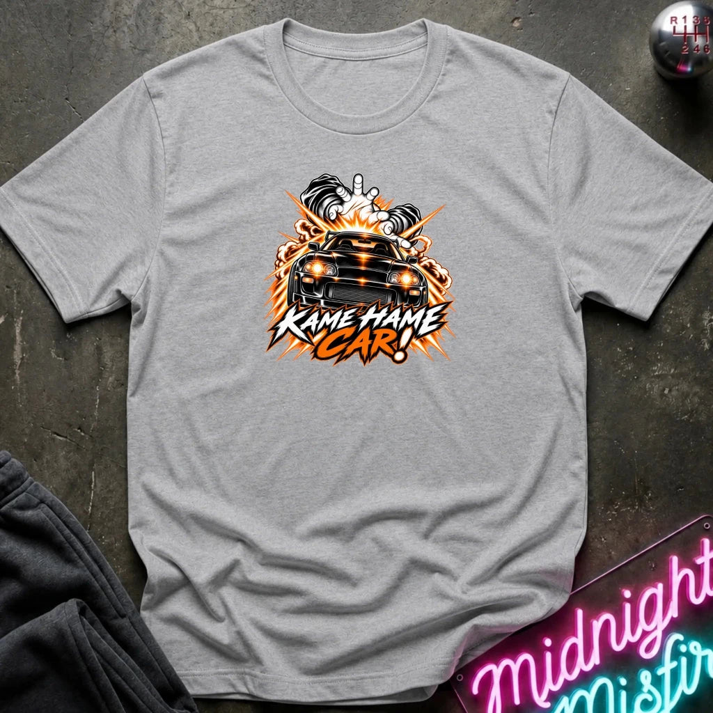 gray short-sleeve graphic t-shirt laid flat on a dark textured surface. The shirt features a red, white, and black graphic of a car with the text 'KAME HAME CAR!' in stylized lettering.