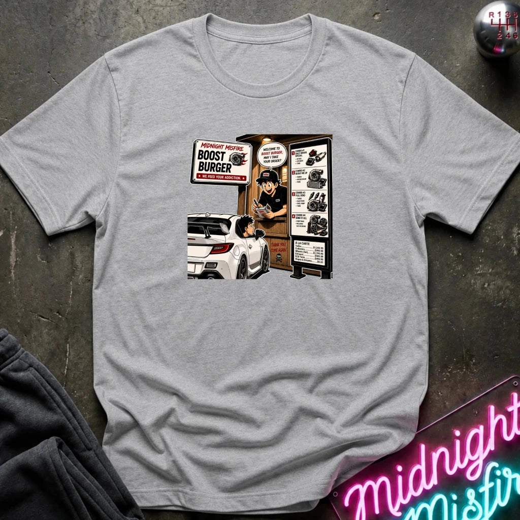 A light gray heather short-sleeve crewneck t-shirt with a retro-style graphic print on the front depicting a fast-food burger scene with a car and a sign reading 'BOOST BURGER'. 