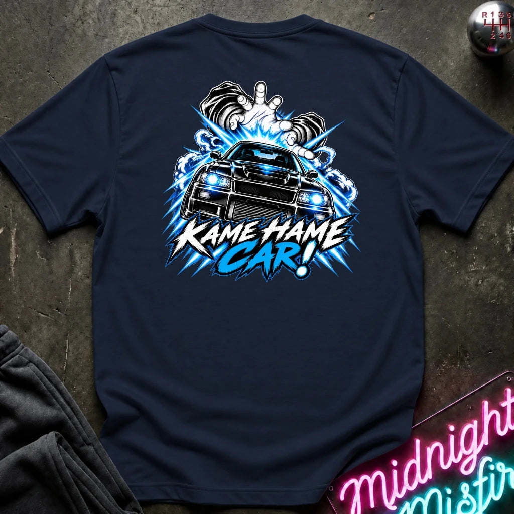 A navy blue t-shirt laid flat on a dark textured surface, featuring a large graphic print on the back with a black car, blue lightning effects, and the text 'KAME HAME CAR!'. 