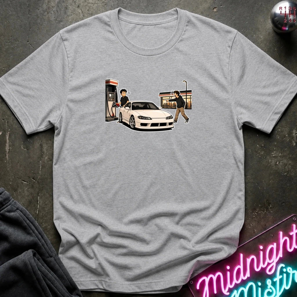 A heather gray short-sleeve t-shirt laid flat on a dark textured surface, featuring a graphic print of a white sports car with a phone booth and two figures. 