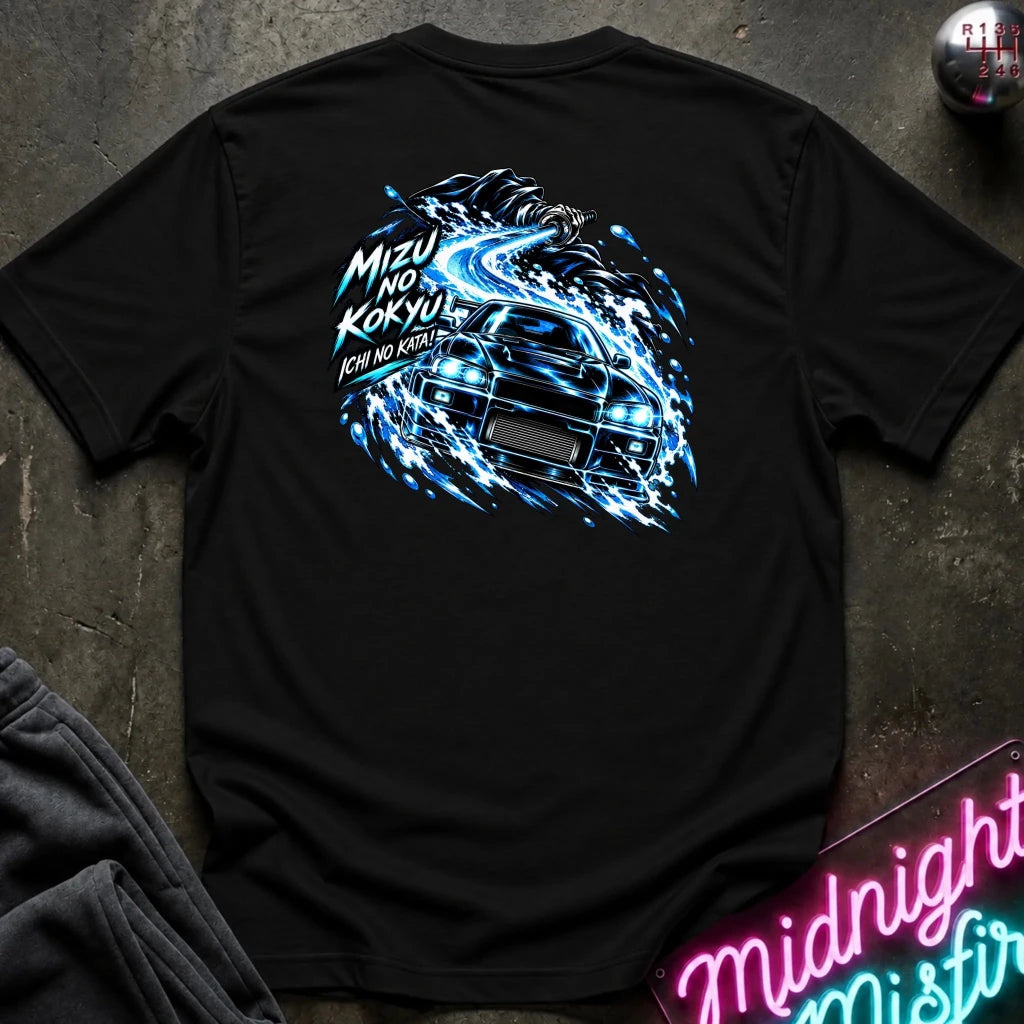 A black short-sleeve t-shirt laid flat on a dark textured surface, showing the back graphic with a car and the text "ichi no kata!"