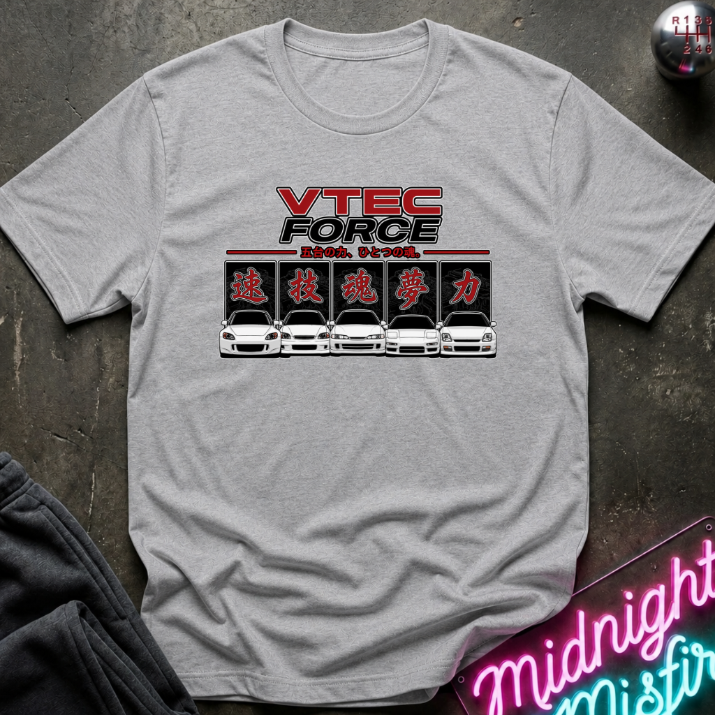 A light gray heather crewneck t-shirt featuring a 'VTEC FORCE' car graphic on the chest, laid flat on a dark textured surface with a neon sign and dark pants partially visible.