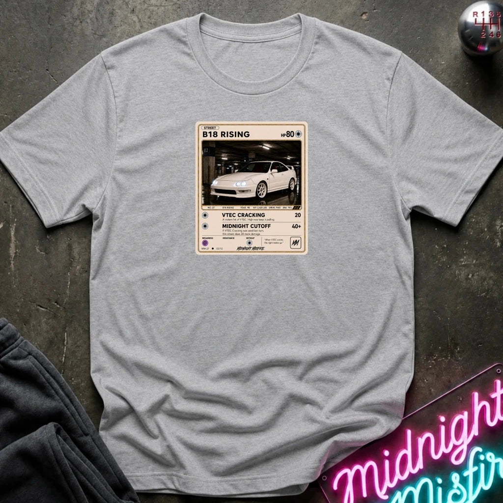 grey crewneck t-shirt laid flat on a dark textured surface. The shirt features a graphic print styled like a retro card
