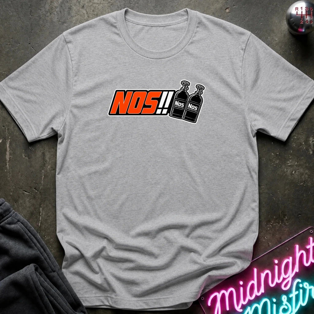A heather gray short-sleeve t-shirt laid flat on a dark textured surface, featuring a graphic print of the word 'NOS!!' in orange and black next to two black spray bottles. 