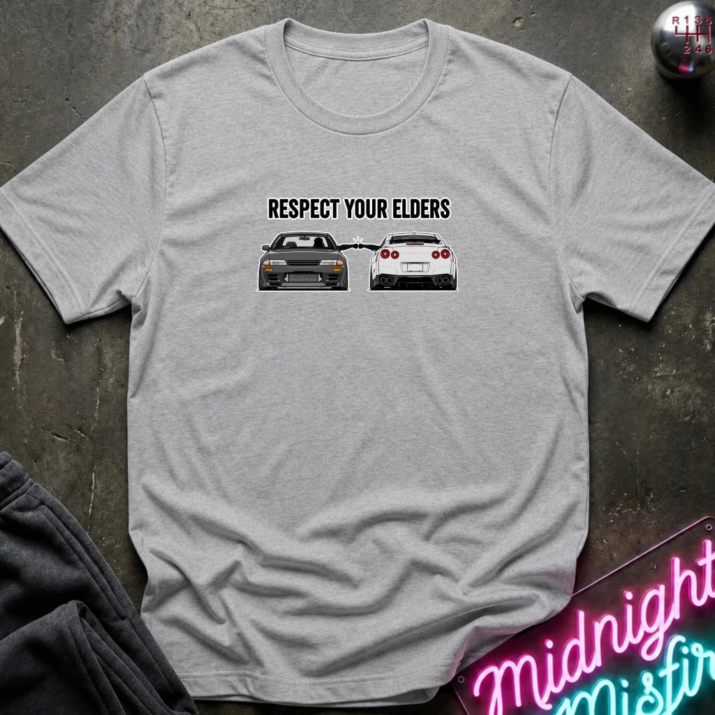 grey graphic t-shirt laid flat on a dark textured surface. The graphic features the text and blue car facing a white car.