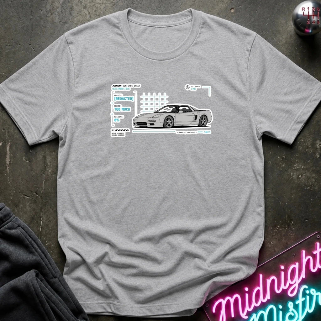 A heather gray short-sleeve t-shirt with a graphic print of a white sports car and its reflection in a window, laid flat on a dark textured surface with a neon sign and dark pants partially visible.